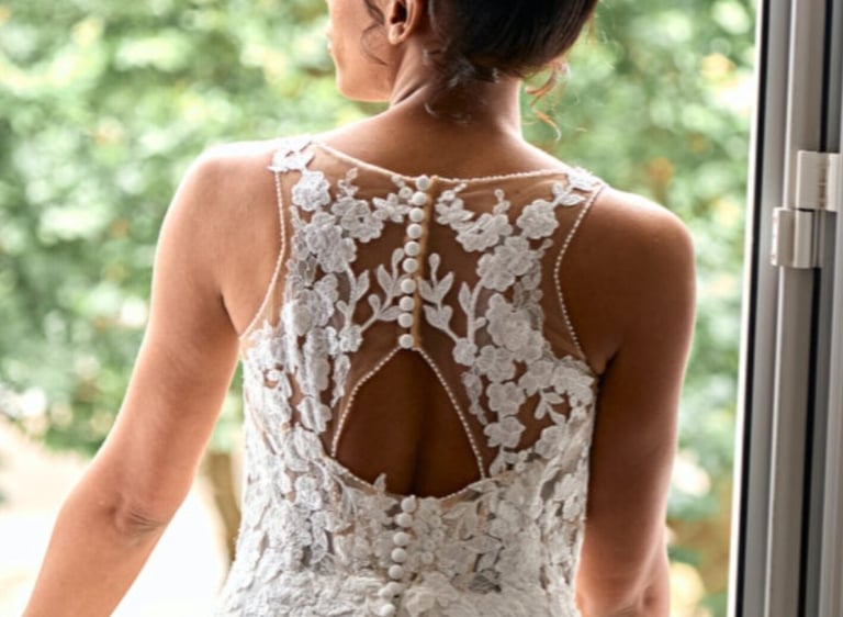 A woman in a wedding dress standing in front of a window