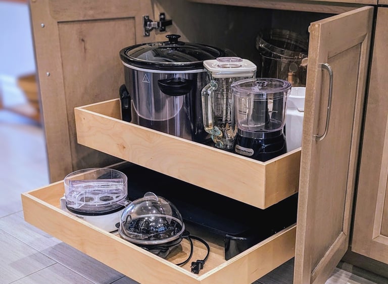 A cabinet drawer is extended out from the cabinet showing heavy kitchen appliances.