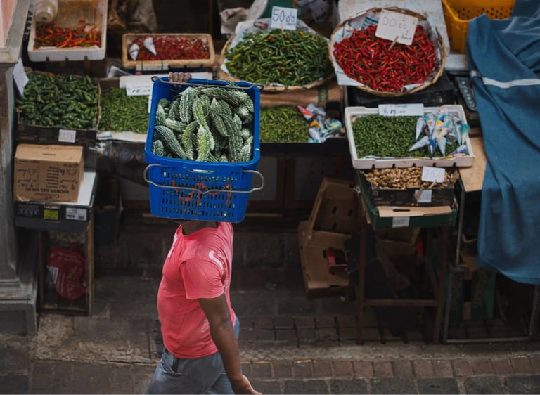 Vendor in Port Louis market carrying a basket of bitter gourds on his head