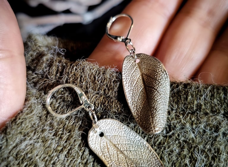 eine Person hält zwei Salbeiblattohrringe aus Silber in der Hand