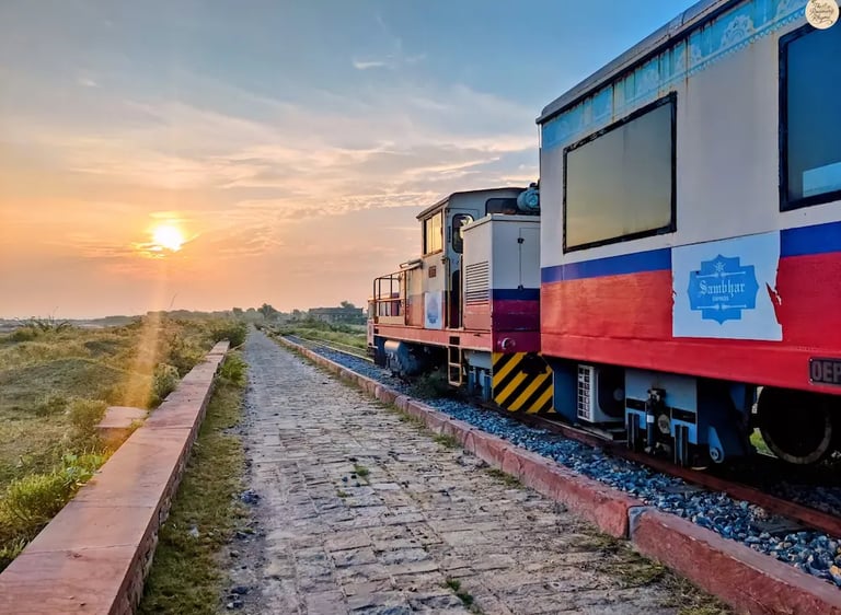 Heritage narrow-gauge train crossing Sambhar Lake at sunrise, bathed in golden light.