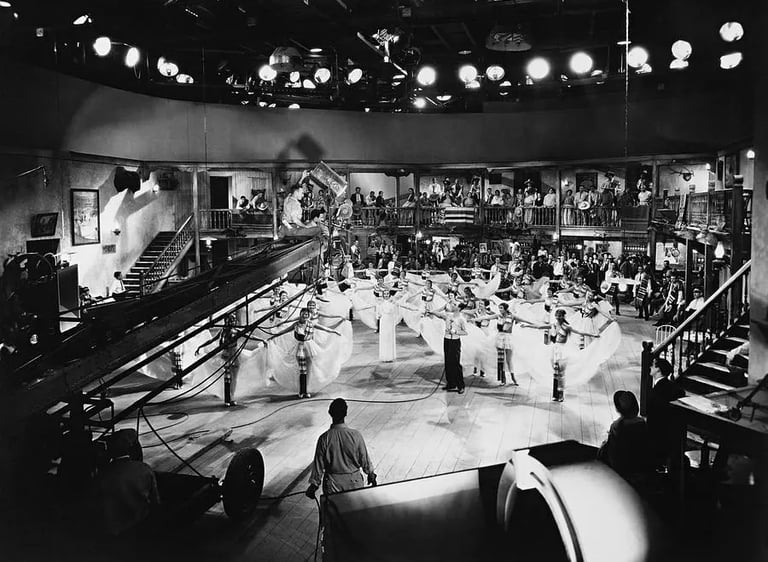 Berkeley on a crane with camera crew, filming white‑skirted dancers in geometric layout.