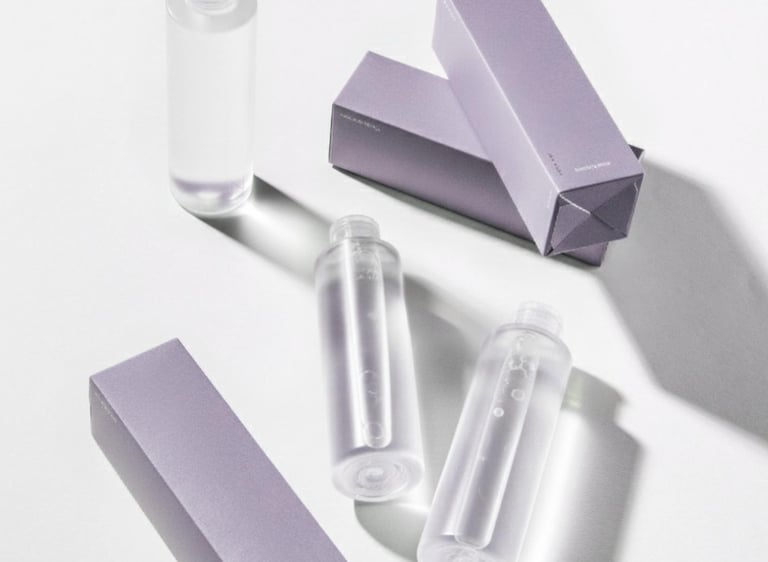 Clear skincare toner bottles with minimalist purple packaging boxes on a white background.