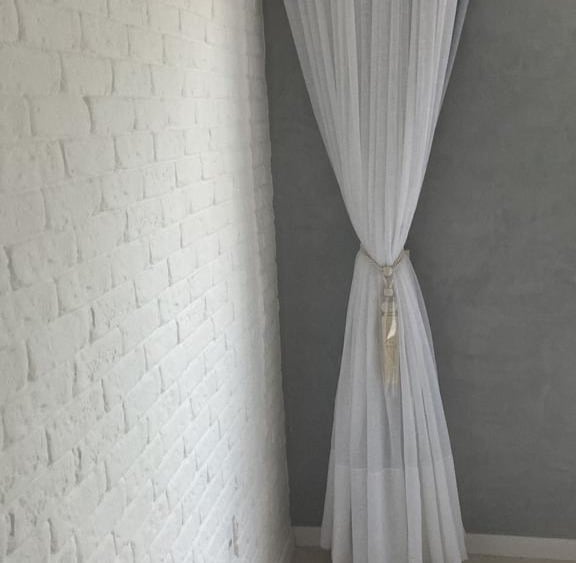 a white curtain with a curtain hanger in a room