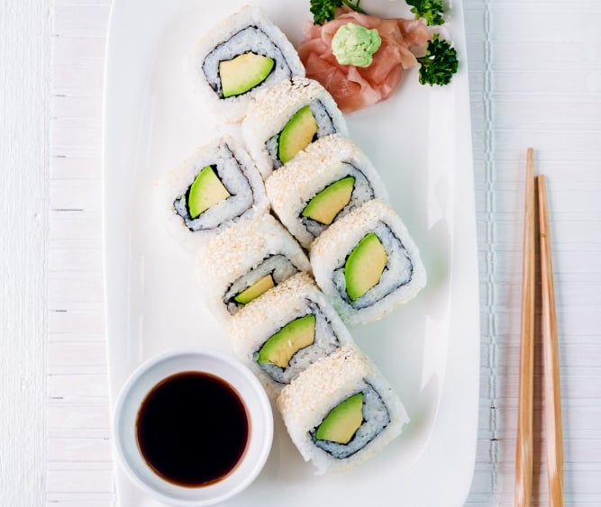 a plate of sushi rolls and chopsticks