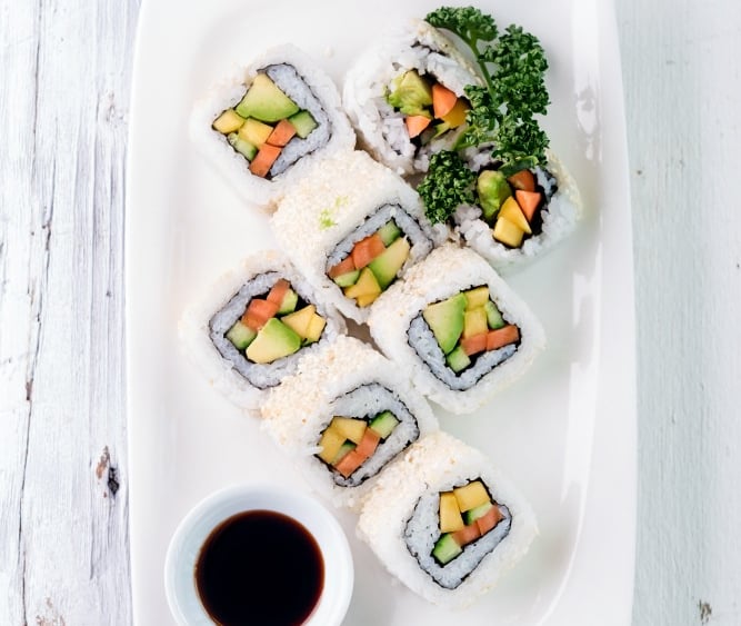 a plate of sushi rolls with sauce and sauce
