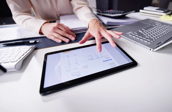 mãos digitando em tablet trabalhand com outros equipamentos proximos