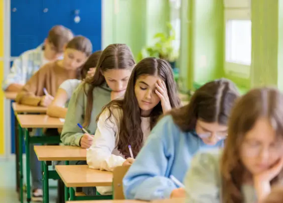 jeunes installés dans une salle, qui passent un examen écrit 