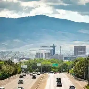 Aerial view of cars driving on a highway toward the Boise skyline with mountains in the background.