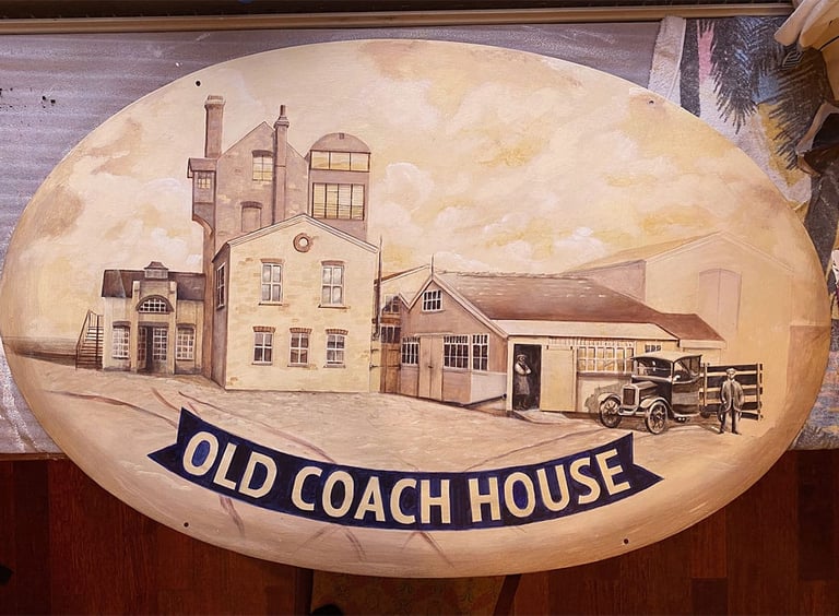 Close-up of pub sign with painted brewery building