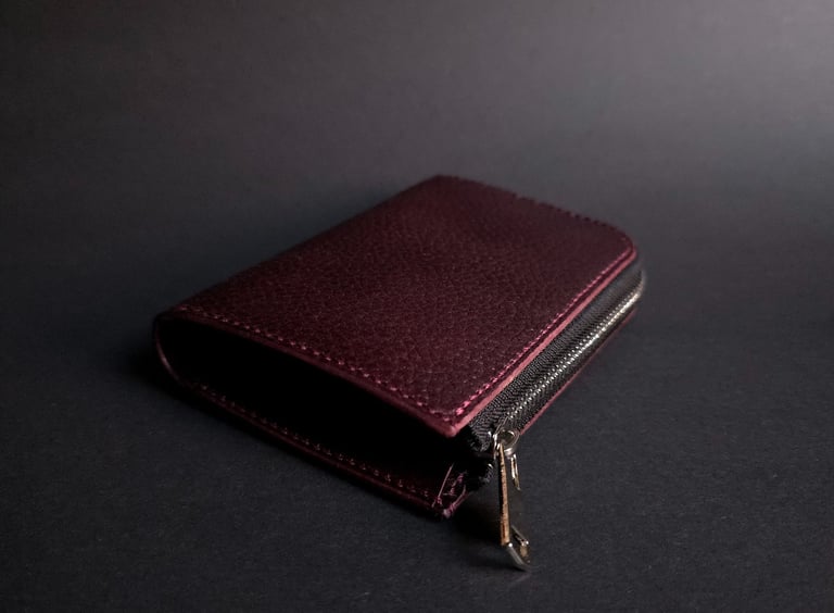 Handmade vegetable tanned leather wallet in burgundy. L-shape wallet in black background.