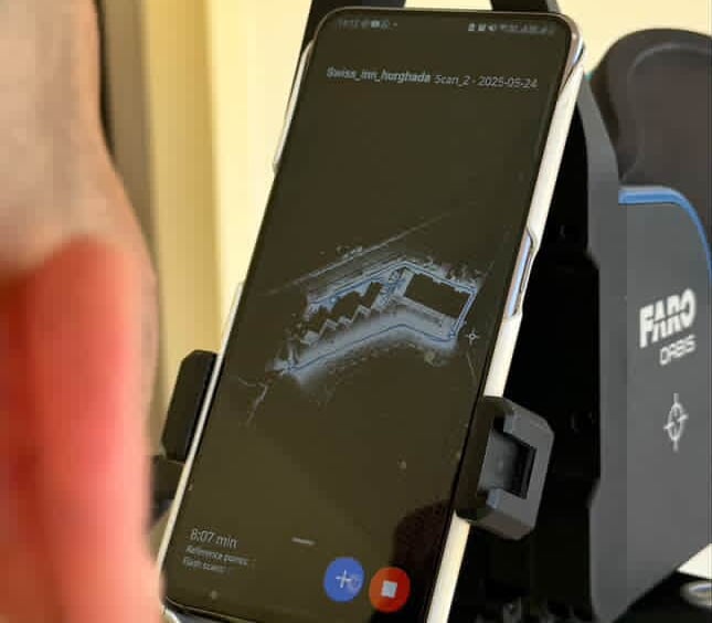 A smartphone mounted on a FARO Orbis laser scanner displaying a real-time 3D floor plan point cloud.