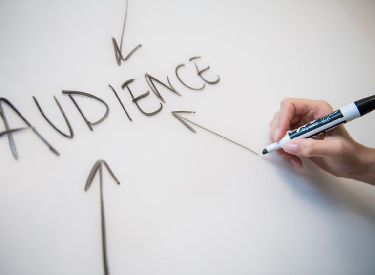 Woman's hand writing the word "audience" on a whiteboard, with arrows. - Swrill