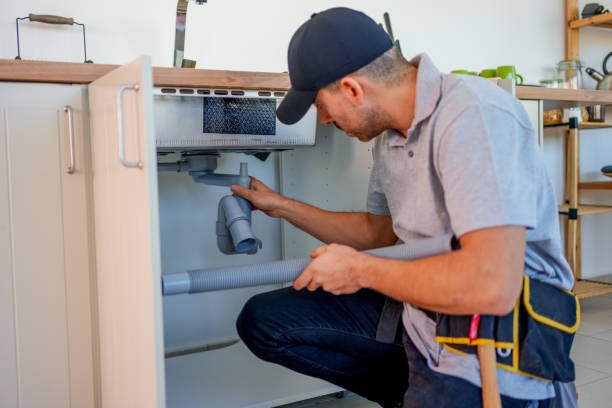 plumber working on a drain under a sink