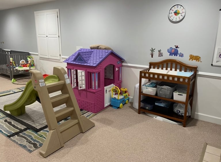 Daycare room with pink toy house and green slide, including baby changing table