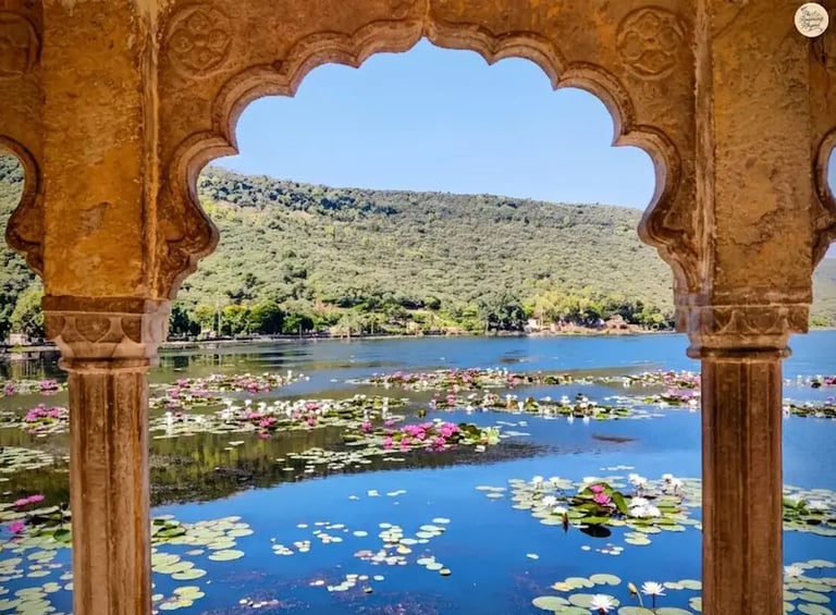 View of Jait Sagar Lake framed through the ornate arches of Sukh Mahal in Bundi.