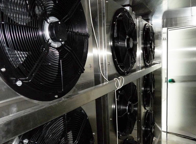 Industrial refrigeration system with multiple high-powered cooling fans in a stainless steel walk-in freezer.