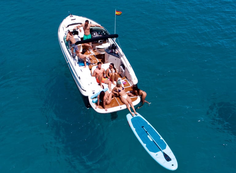 Gruppe genießt ein Boot mit Paddle Surf in kristallklarem Wasser auf Mallorca