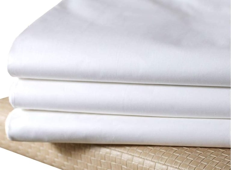a stack of white sheets and pillows on a bed