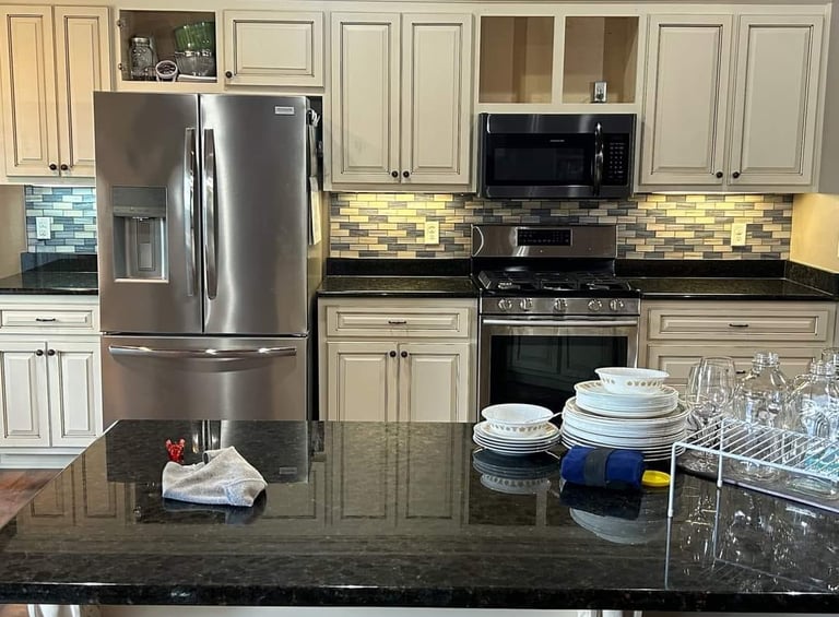 Kitchen remodel with white cabinets, stainless steel appliances, and a dark countertop island.