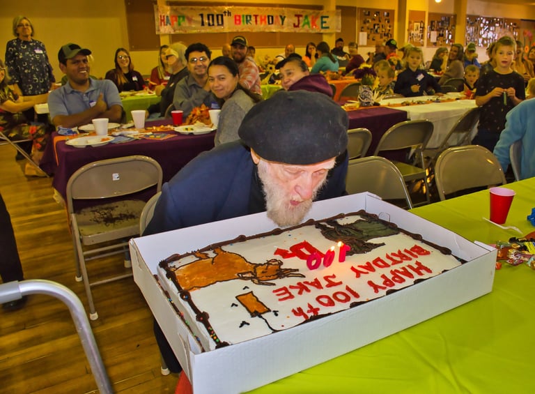 a man blowing out a candle on a cake for his birthday