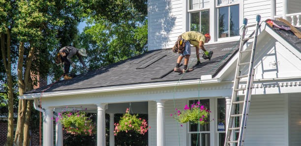 white house with a man ont he roof installing new roof tiles with a white ladder in the photo