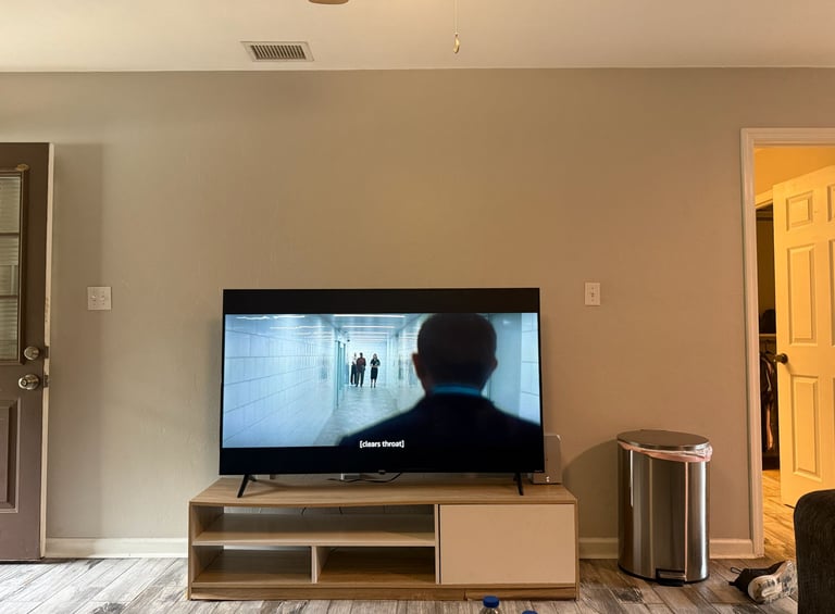 Modern flat screen TV on a wood entertainment center in a living room with beige walls.