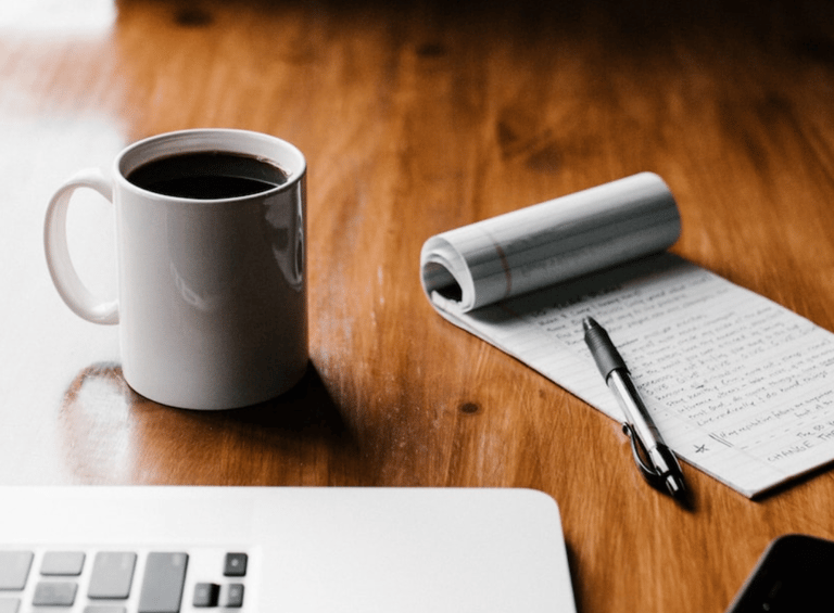 a cup of coffee and a notebook on a table