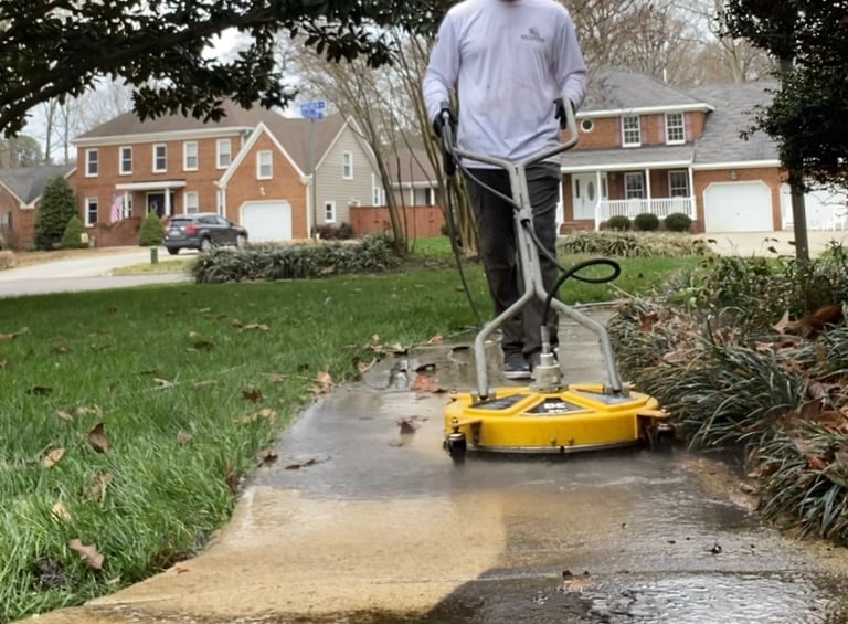 Professional pressure washing service cleaning a residential concrete sidewalk with a surface cleaner.