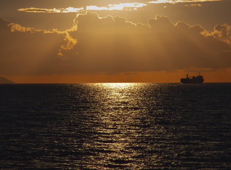 a ship sailing in the ocean at sunset