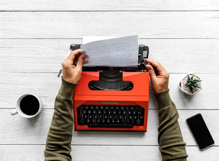 A writer typing on a typewriter, with a focus on the writing process and content creation.