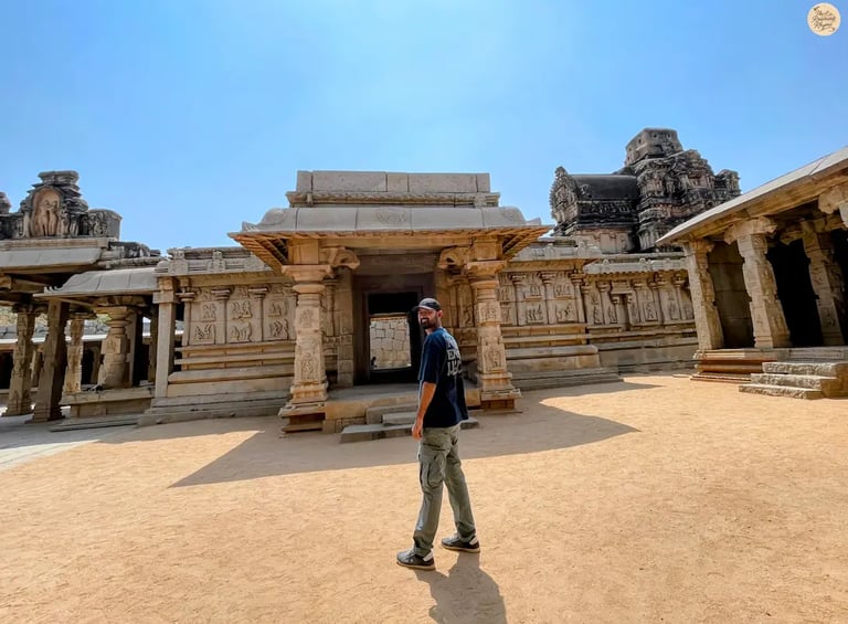 Person standing at Hazara Rama Temple in Hampi, with walls depicting Ramayana carvings.