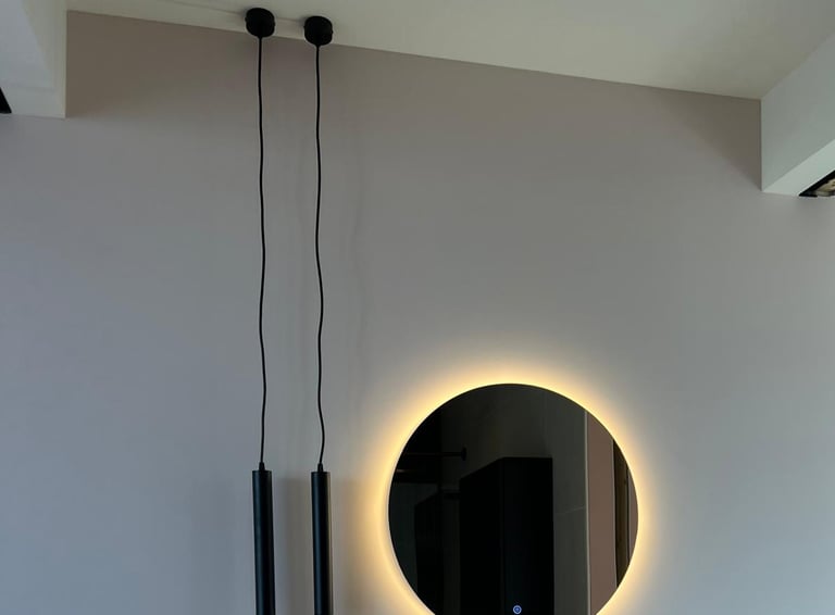 Moderne badkamer met een ronde LED-spiegel en een zwevende designwastafel.