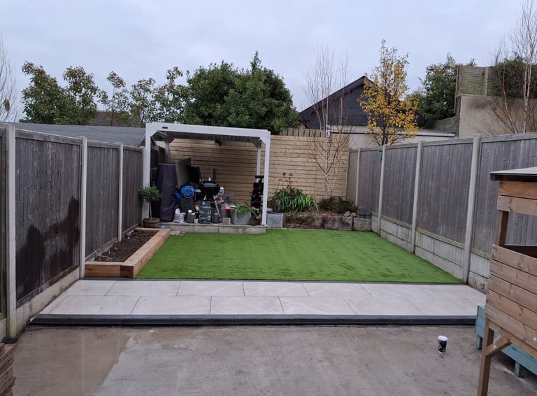 a backyard patio with a green lawn and a small garden