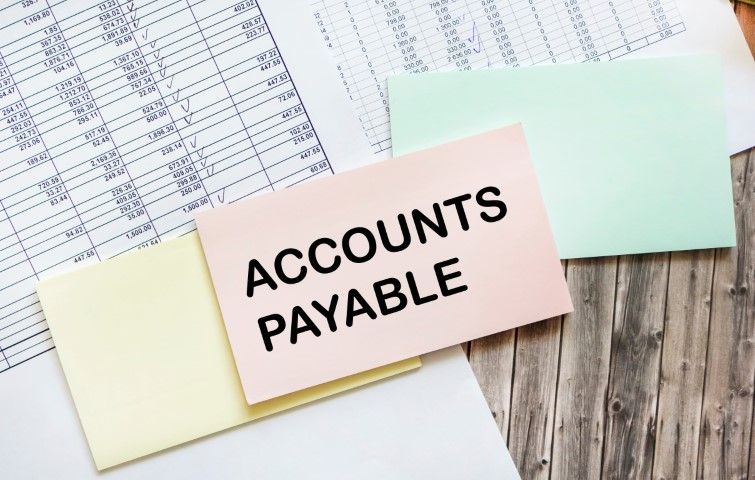 A sticky note that says `` accounts payable '' is sitting on top of a pile of papers.