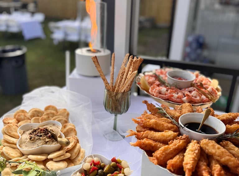 Servicio de catering gourmet con camarones fritos, hummus y aperitivos de cóctel en un evento 