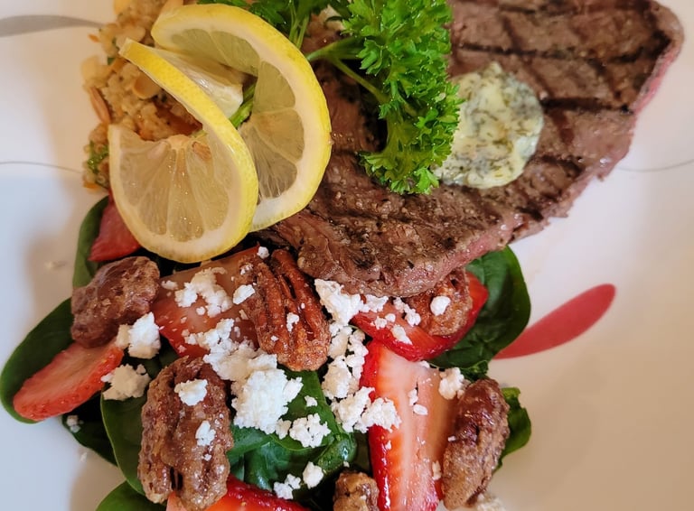 Beautifully garnished steak with compound butter and spinach, strawberry, pecan, goats cheese saladl
