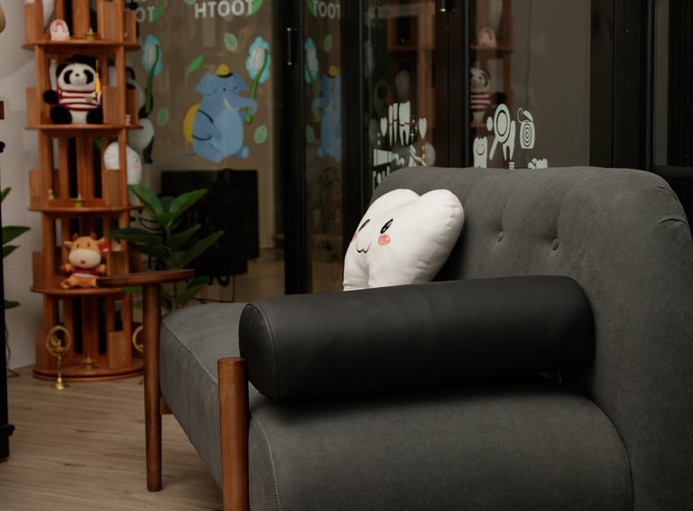 Modern dental clinic reception area with comfortable couches, tooth-shaped pillows, and a sleek wood