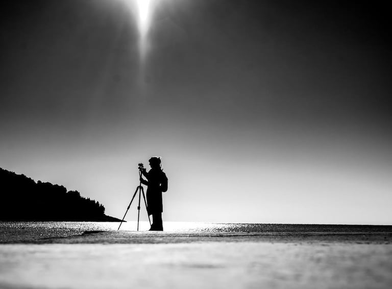 Tina Bikic holding a camera, black and white artistic portrait.