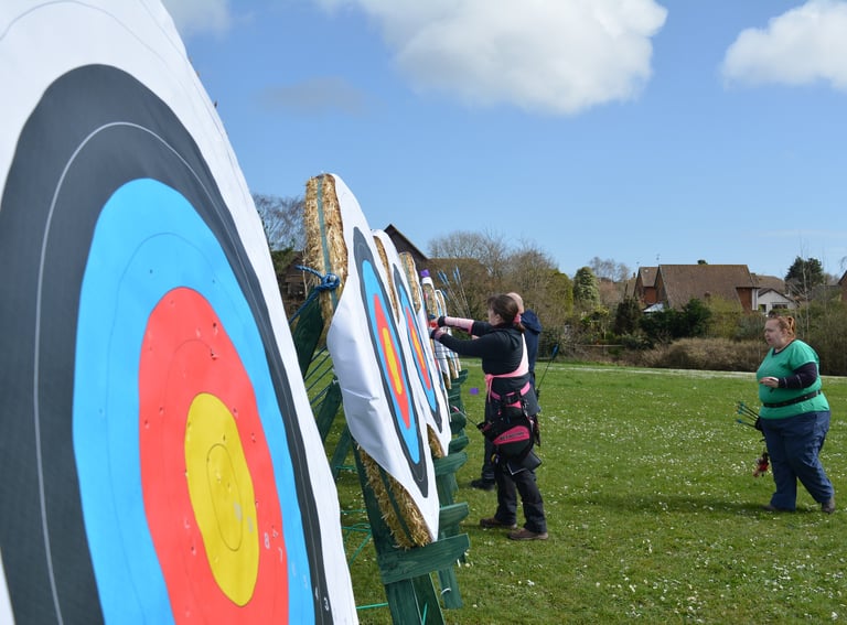 a man and woman are standing in front of an archery target