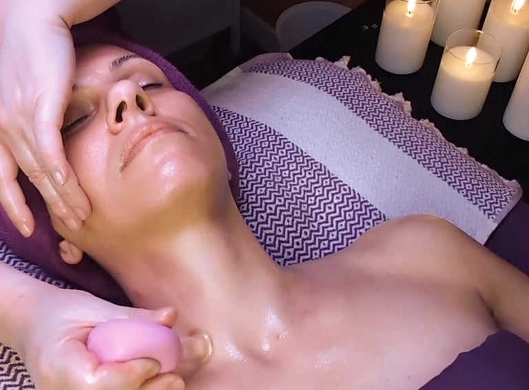 Professional facial massage with pink cupping tool and candles for a relaxing spa treatment.