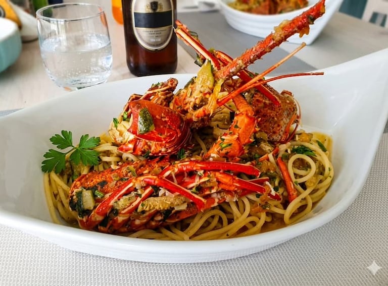 Spaghetti conditi con aragosta e pomodorini serviti in un piatto bianco di design.