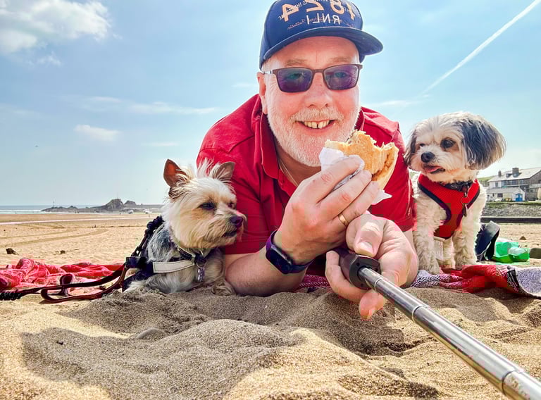 a man in a red shirt and two togs on a Cornish beach 