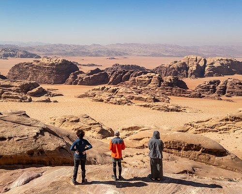 two people standing on a rocky cliff overlooking the desert