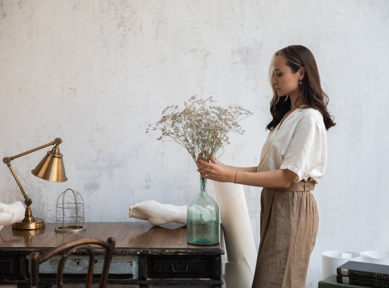 a woman putting dried foliage into a vase