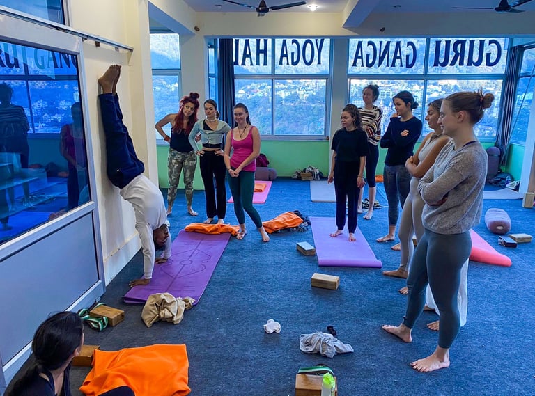 Yoga students practicing asanas together under the guidance of their teacher during a training session in Rishikesh, India.