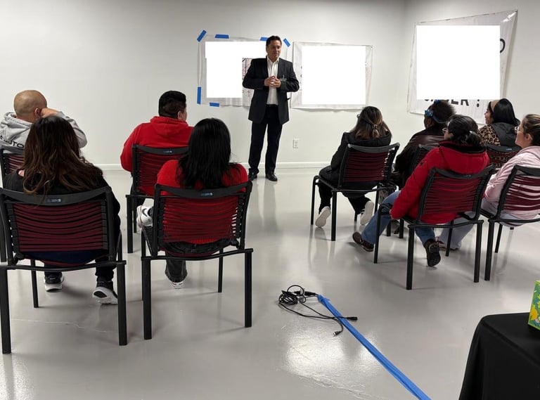 Professional business seminar with a speaker presenting to a diverse group of seated workshop participants.