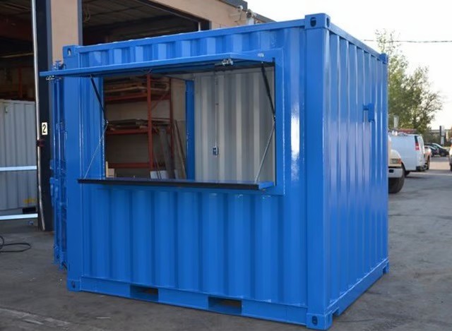 Blue modified shipping container kiosk with an open service window for a pop-up shop.
