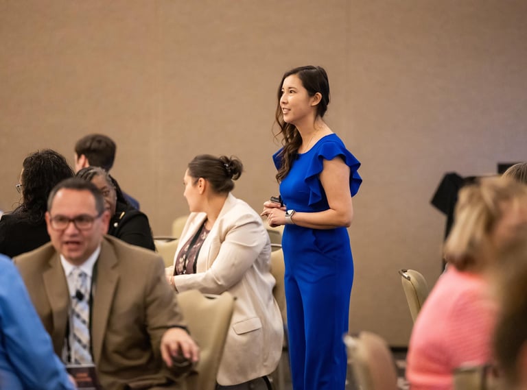 Woman in blue jumpsuit leading an Unleashing Radiance empowerment event for professional women.