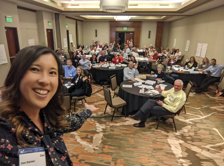 Smiling woman hosting Unleashing Radiance workshop with large audience